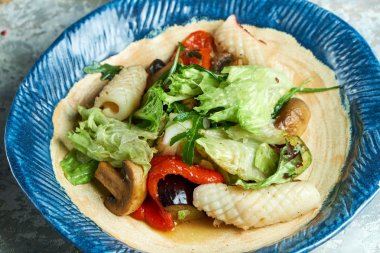 Kalamarlı sebze salatası. Güzel servis yemekleri. Açık gri arka plan. Restoran menüsü