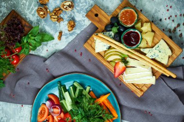 Açık gri bir arka plan üzerinde: sebze ve peynir tabağı ile bir tahta ile bir tabak. Yemeklerin güzel bir porsiyon. Restoran menüsü