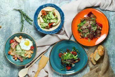Farklı salatalar ile çok renkli tabaklar. Yemeklerin güzel bir porsiyon. Açık gri arka plan. Restoran menüsü