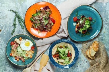 Farklı salatalar ile çok renkli tabaklar. Yemeklerin güzel bir porsiyon. Açık gri arka plan. Restoran menüsü