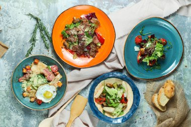 Farklı salatalar ile çok renkli tabaklar. Yemeklerin güzel bir porsiyon. Açık gri arka plan. Restoran menüsü