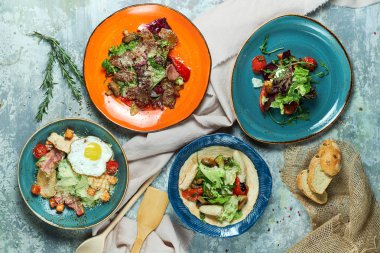 Farklı salatalar ile çok renkli tabaklar. Yemeklerin güzel bir porsiyon. Açık gri arka plan. Restoran menüsü