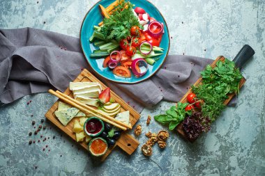 Açık gri bir arka plan üzerinde: sebze ve peynir tabağı ile bir tahta ile bir tabak. Yemeklerin güzel bir porsiyon. Restoran menüsü