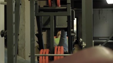Spor salonunda simülatörde bacak presleri yapan aşırı kilolu bir adam. Fitness eğitimi. Sağlıklı yaşam tarzı kavramı