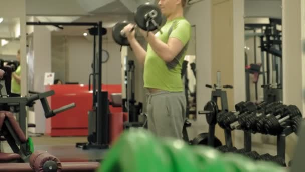 A overweight man lifts an ez barbell while standing at the gym. Exercise for biceps. Fitness. Healthy lifestyle. — Stock Video