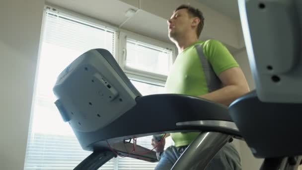 Een overgewicht man op een loopband in een sportschool. Fitness. Gezonde levensstijl — Stockvideo