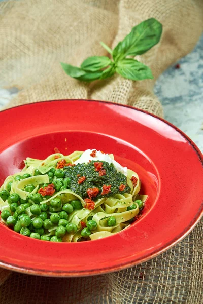 Espaguetis con guisantes verdes frescos. Fondo texturizado gris con tejido beige. Hermosa porción de platos. Menú restaurante — Foto de Stock