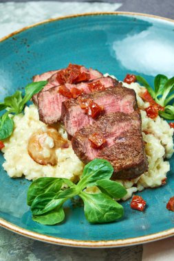 Biftekli beyaz pirinç. Rizzotto. Gri ışıklı arka plan. Güzel yemek servisi.