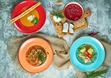 Farklı çorbalar ile çok renkli tabaklar. Gri ışık dokulu arka plan. Güzel servis yemekleri. Restoran menüsü