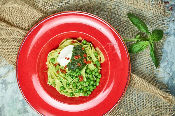 Spagettia tuoreilla vihreillä herneillä. Harmaa kuvioitu tausta beige kangas. Kaunis tarjoilu ruokia. Ravintolan menu — kuvapankkivalokuva