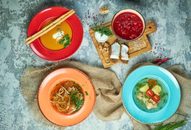 Farklı çorbalar ile çok renkli tabaklar. Gri ışık dokulu arka plan. Güzel servis yemekleri. Restoran menüsü