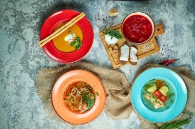 Farklı çorbalar ile çok renkli tabaklar. Gri ışık dokulu arka plan. Güzel servis yemekleri. Restoran menüsü