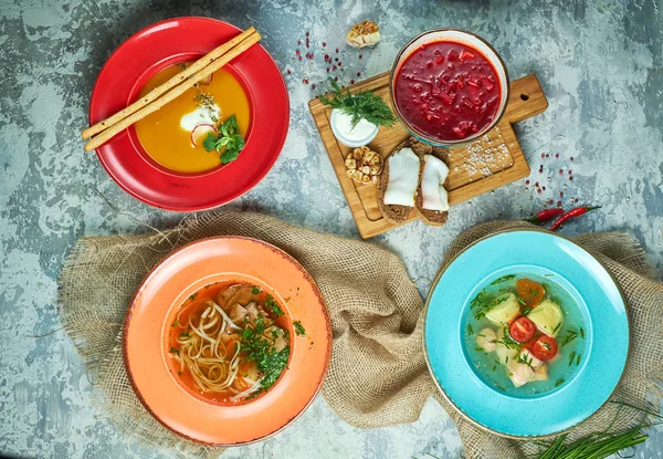 Farklı çorbalar ile çok renkli tabaklar. Gri ışık dokulu arka plan. Güzel servis yemekleri. Restoran menüsü