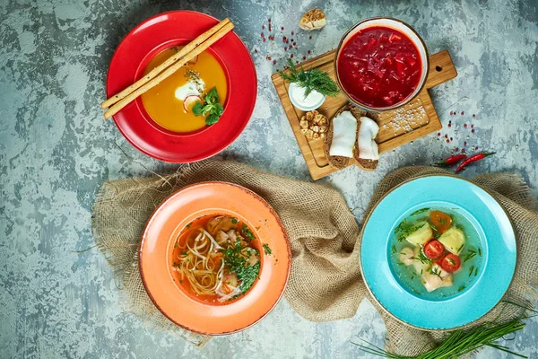 Farklı çorbalar ile çok renkli tabaklar. Gri ışık dokulu arka plan. Güzel servis yemekleri. Restoran menüsü