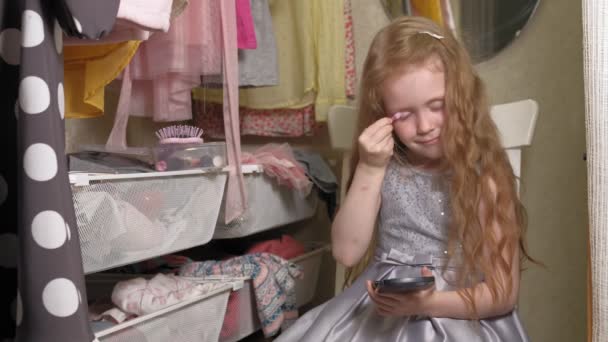 Mooi klein meisje zet make-up op het gezicht. Modieuze kinderen. — Stockvideo