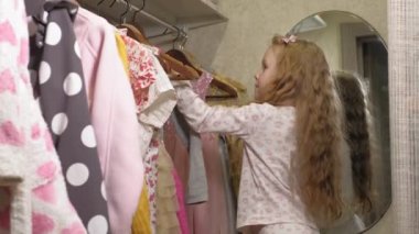 Güzel küçük kız ev gardırop elbise seçer. Güzellik ve moda