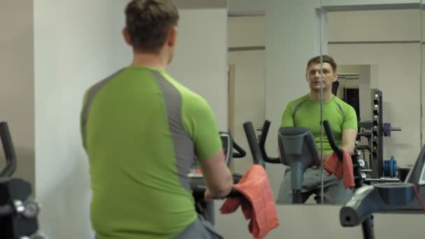 Άνθρωπος στο ποδήλατο γυμναστικής στο γυμναστήριο. Έννοια του υγιεινού τρόπου ζωής — Αρχείο Βίντεο