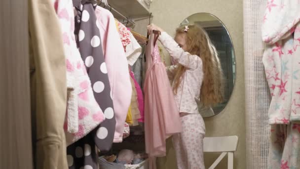 Hermosa niña elige el vestido en el armario del hogar. Belleza y moda — Vídeo de stock