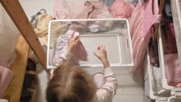 Klein meisje ruimt kleren in thuis garderobe — Stockvideo