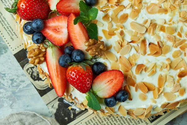 Tarta de merengue de fresa con pétalos de almendra, en el periódico —  Fotos de Stock