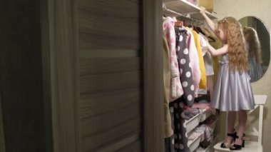 Güzel küçük kız ev gardırop elbise seçer. Güzellik ve moda