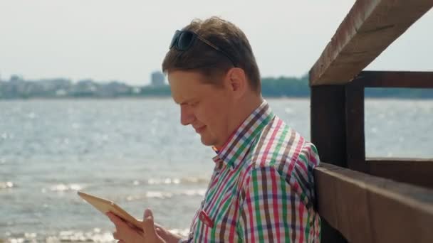 Человек на пляже пользуется планшетом . — стоковое видео