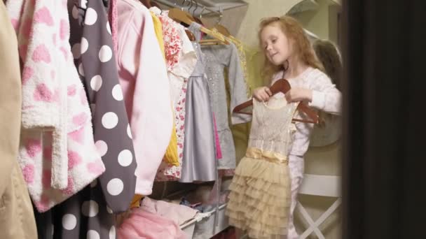 Mooi klein meisje kiest jurk in Home garderobe. Schoonheid en mode — Stockvideo