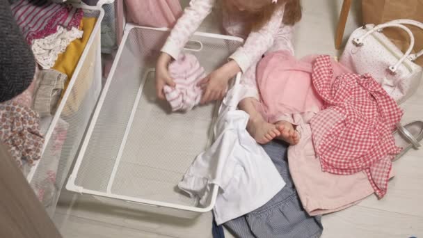Little girl cleans up clothes in home wardrobe — Stock Video