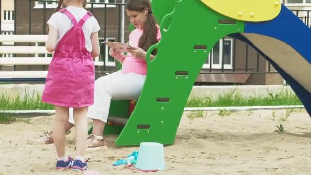 Los niños usan una tableta de computadora, caminan en el patio de recreo — Vídeo de stock