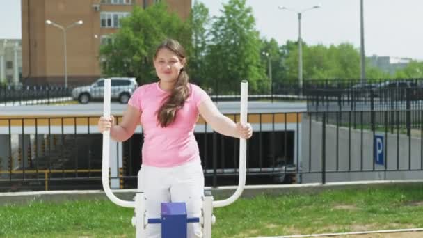 Дівчина-підліток на відкритому сайті з тренажерами. здоровий спосіб життя — стокове відео