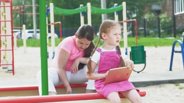 I bambini usano un tablet per computer, camminano nel parco giochi — Video Stock