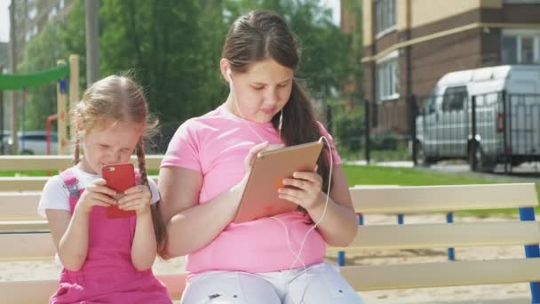Adolescente niña preescolar utilizando dispositivos móviles al aire libre — Vídeo de stock