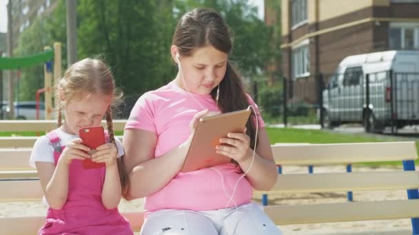 Adolescente niña preescolar utilizando dispositivos móviles al aire libre — Vídeos de Stock