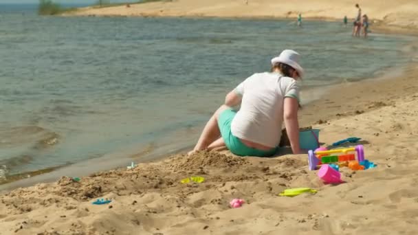 Flickan bygger ett sandslott på flodbanken — Stockvideo