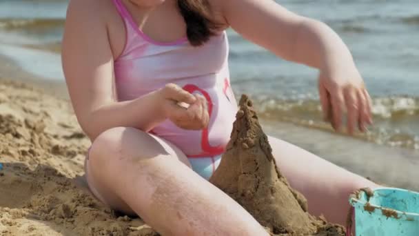 Fille construit un château de sable sur la rive de la rivière — Video