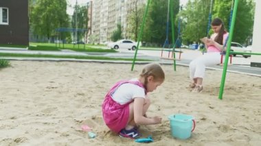 Çocuklar bilgisayar tableti kullanır, oyun alanında yürürler.