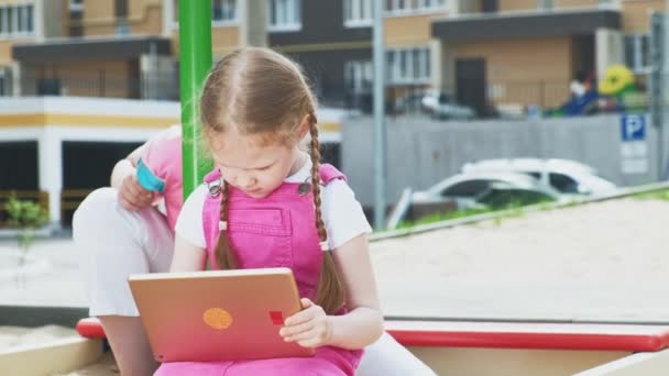 As crianças usam um tablet de computador, caminham no playground — Vídeo de Stock
