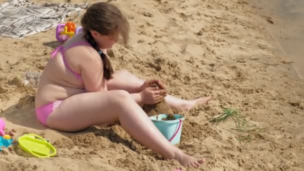 Menina constrói um castelo de areia na margem do rio — Vídeo de Stock