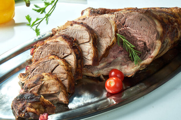 A piece of baked red meat sliced on an oval plate. Beautiful serving dishes. Restaurant menu