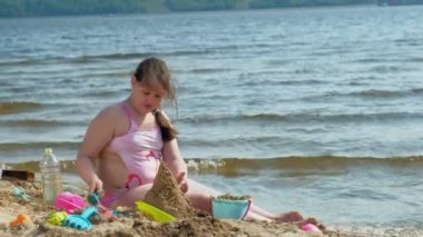  Kız nehir kıyısında bir kum dansı inşa ediyor.