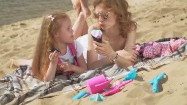 Nehir kıyısındaki anne ve kızı dondurma yiyor. Açık hava rekreasyon