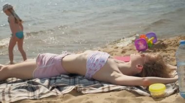 Genç kadın plajda yatıyor.