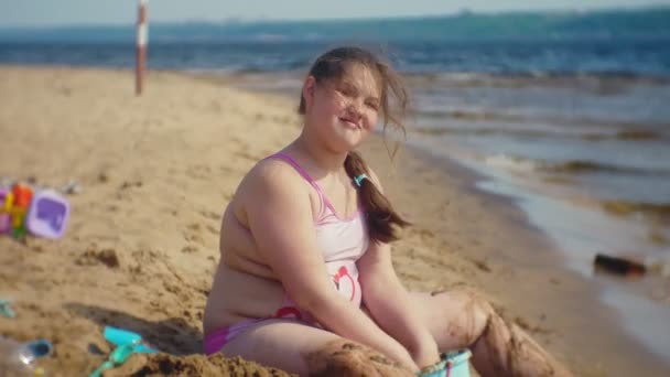 Menina constrói um castelo de areia na margem do rio — Vídeo de Stock