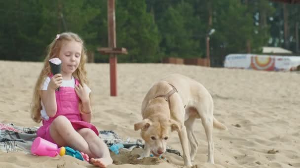 Mädchen isst Eis und füttert Hund im Freien. — Stockvideo