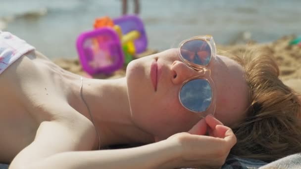 年轻女子躺在海滩上 — 图库视频影像