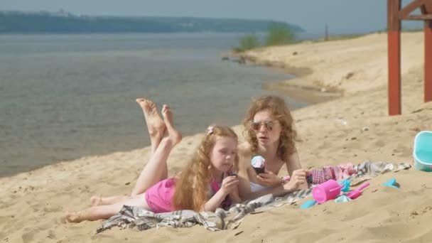 Mutter und Tochter am Flussufer essen Eis. Freizeitgestaltung im Freien — Stockvideo