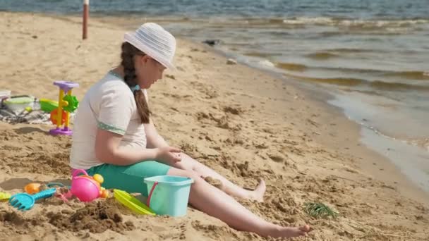 Fille construit un château de sable sur la rive de la rivière — Video