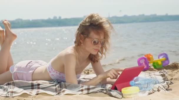 Ung kvinna använder datorplatta på stranden, flodbanken — Stockvideo