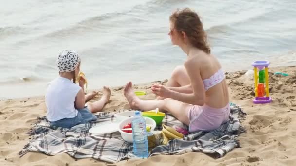 Güneşli bir günde nehir kenarında bir piknik kızı ile anne — Stok video