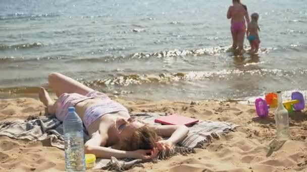 Νεαρή γυναίκα ξαπλωμένη στην παραλία — Αρχείο Βίντεο
